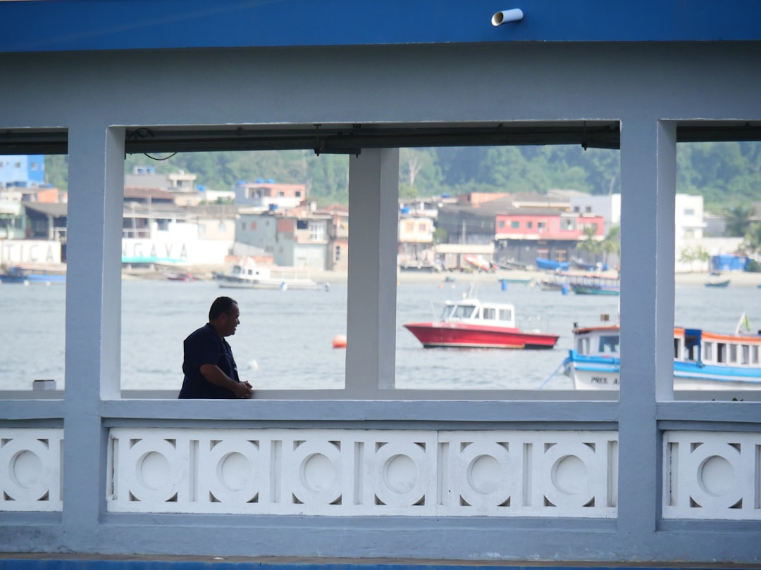A professional sitting at a minimalist desk inside a modern home, looking thoughtfully out a large window at a serene lake, symbolizing the analysis and planning of a real estate investment.
