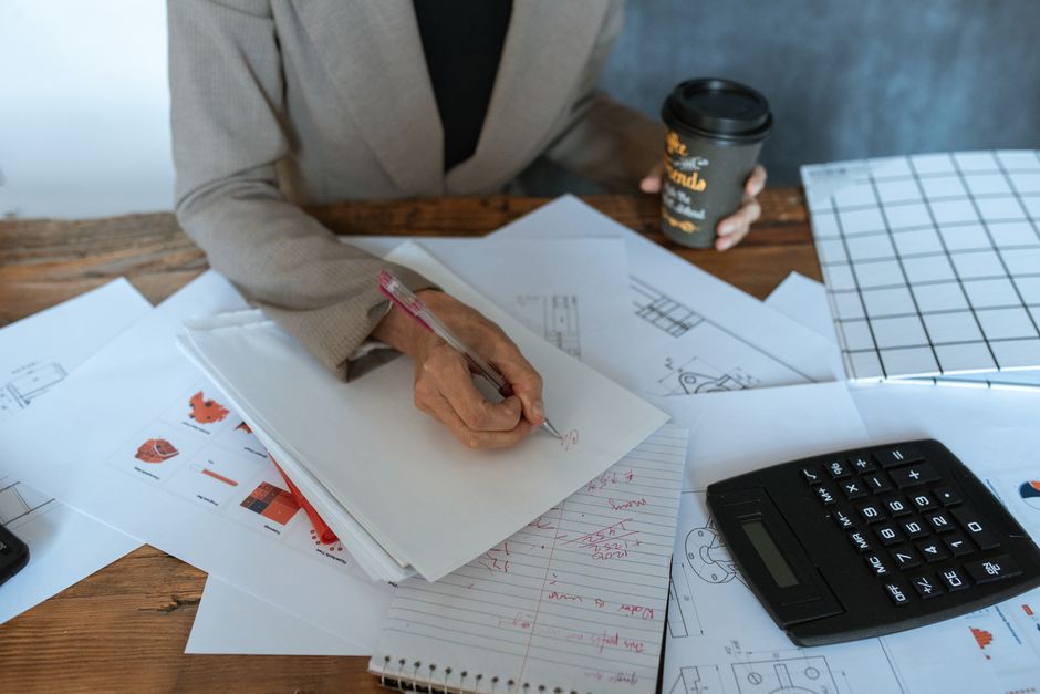 A clean and modern desk with a miniature house model, a calculator, and blueprints, representing a professional and analytical approach to the real estate market.