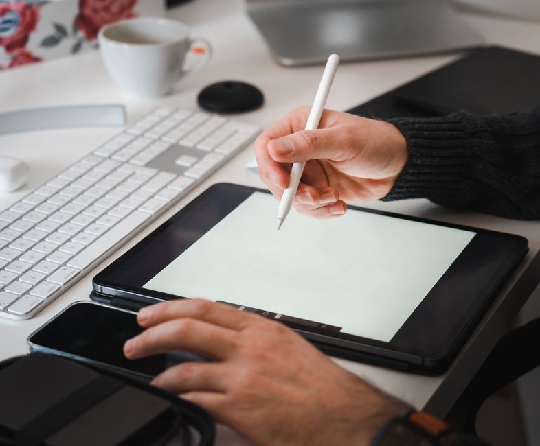 A professionally dressed person reviewing information on a tablet inside a modern, luxurious home with a beautiful coastal view visible in the background.
