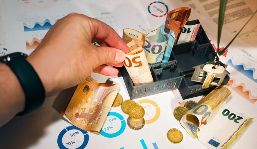 Set of house keys and a small stack of coins arranged neatly on a modern, clean desk, symbolizing the financial aspect of ...