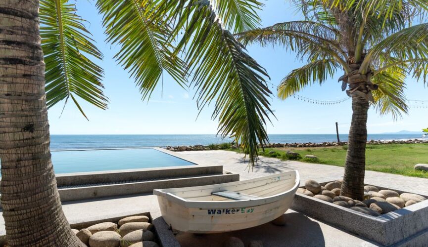 Stunning modern villa with an infinity pool overlooking the iconic coastline and blue ocean of Los Cabos, Mexico at sunset.